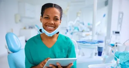 a hero image of a clinician in a dental surgery, holding a tablet computer
